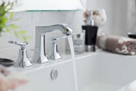 Water pouring out of modern bathroom faucet.