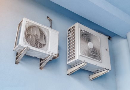 White air conditioners on the blue wall of the house.